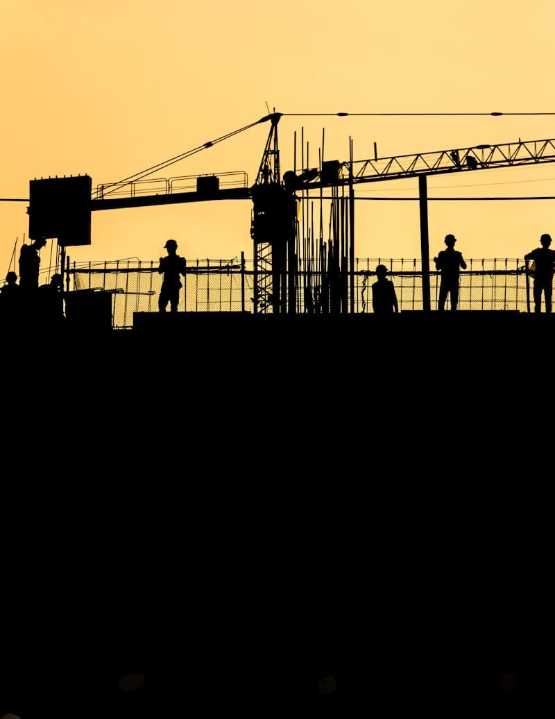Construction crew silhouetted against the evening sky