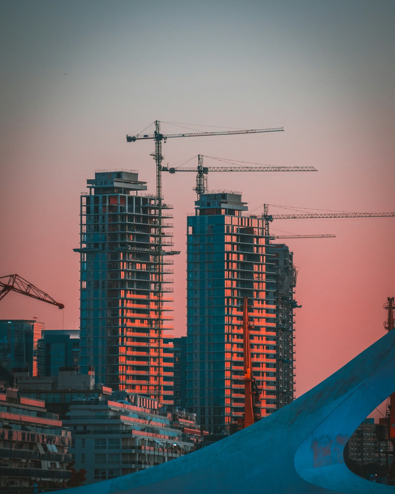 High-rise building under construction with tower cranes at golden hour